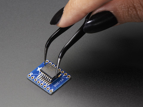 A pair of tweezers holding a microchip hovers over the SMT Breakout PCB for SOIC-16 or TSSOP-16.