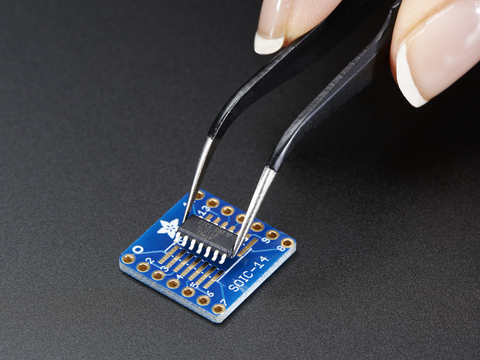 A pair of tweezers holding a microchip hovers over the SMT Breakout PCB for SOIC-14 or TSSOP-14.