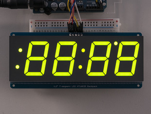 Huge green 7-segment clock display soldered to backpack with all segments lit