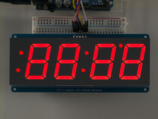 Huge red 7-segment clock display soldered to backpack with all segments lit