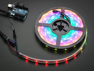 Adafruit NeoPixel Digital RGB LED Strip reel wired to a microcontroller, with all the LEDs in a rainbow