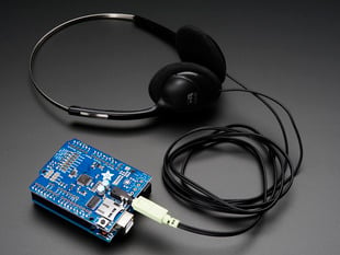 Angled shot of Adafruit "Music Maker" MP3 Shield for Arduino connected to a pair of headphones. 