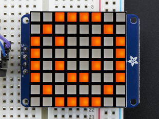 Close-up of Soldered and assembled Small 1.2" 8x8 Ultra Bright Square Amber LED Matrix + Backpack on a breadboard powered by an Arduino Uno. The LED Matrix displays an orange smiley.