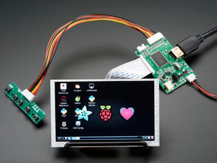 Angled shot of an assembled HDMI 4 Pi: 5" Display (no Touch) w/Mini Driver. The HDMI screen displays a desktop image including the Adafruit logo, the Raspberry Pi logo, and a pink heart.