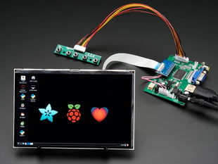 Angled shot of a HDMI 4 Pi: 7" Display. Display. The monitor displays a desktop background with a adafruit logo, raspberry logo, and a heart. 