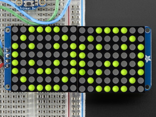 Close-up of Soldered and assembled 16x8 1.2" LED Matrix + Backpack - Ultra Bright Round Yellow-Green LEDs on a breadboard. The LED Matrices display a smiling emoji and a frowning emoji.