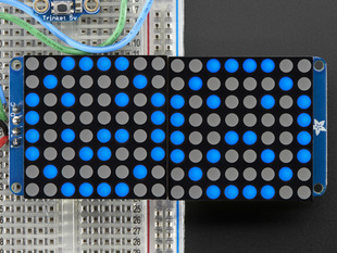 Close-up of Soldered and assembled 16x8 1.2" LED Matrix + Backpack - Ultra Bright Round Blue LEDs on a breadboard. The LED Matrices display a smiling emoji and a frowning emoji.