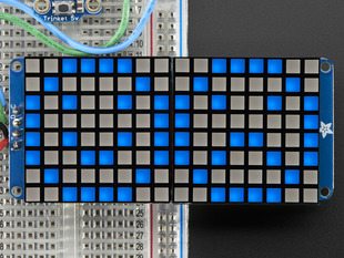 Close-up of Soldered and assembled 16x8 1.2" LED Matrix + Backpack - Ultra Bright Square Blue LEDs on a breadboard. The LED Matrices display a smiling emoji and a frowning emoji.