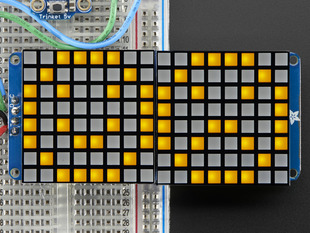 Close-up of Soldered and assembled 16x8 1.2" LED Matrix + Backpack - Ultra Bright Square Yellow LEDs on a breadboard. The LED Matrices display a smiling emoji and a frowning emoji.