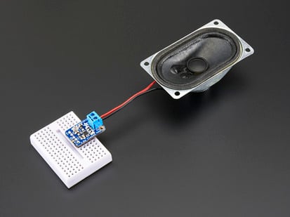 Angled shot of an Adafruit Mono 2.5W Class D Audio Amplifier assembled to a speaker and white breadboard. 