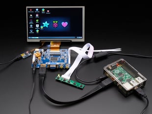 Front shot of a HDMI 4 Pi: 7" Display connected to a Raspberry Pi. The monitor displays a desktop background with a adafruit logo, raspberry logo, and a heart. 