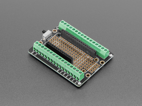 Angled shot of rectangular terminal block breakout board with green terminal blocks.