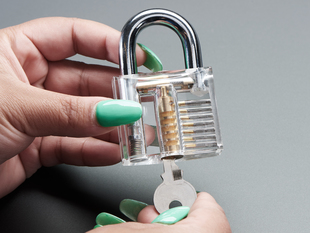 Hands holding clear padlock and opening with a small key.