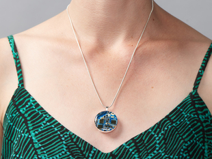 Blue circuit board pendant shown being worn