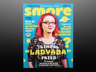 Topdown shot of Smore magazine cover. A bespectacled white woman, Limor Fried a.k.a. Ladyada, in black clothes with pink, shoulder-length hair is on the cover.