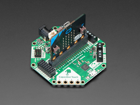 Angled shot of a Adafruit CRICKIT for micro:bit connected to a black squared board.