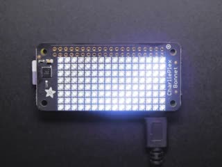 Top down view of a Adafruit CharliePlex LED Matrix Bonnet illuminating cool white. 