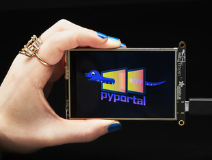 Hand holding PyPortal Titano development board with SAMD51, ESP32 Wifi, and 3.5" touchscreen TFT display.