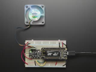 Adafruit EMC2101 I2C PC Fan Controller and Temperature Sensor wired up to Feather with OLED wing and a PC fan. A hand slows down the fan and the RPM display decreases. 