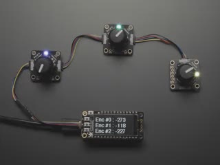 Top view video of a hand turning the rotary encoder knobs on three PCBs. The NeoPixel LEDs on each PCB change color. The OLED display changes its readout data with each twisty-turn.