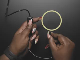 Top view of two Black hands using an on-off switch to turn on a ring light with cool white LEDs. 