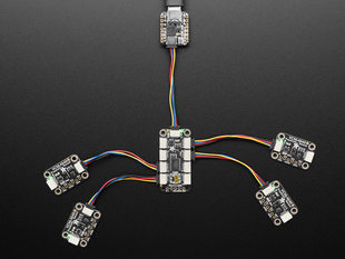 Overhead shot of STEMMA QT breakout board with eight JST-SH ports wired up to four black, rectangular VCNL light sensors. All their indicator LEDs are lit up green.