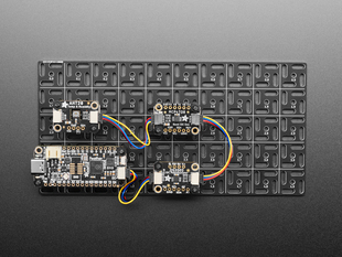 Top shot of a feather, a humidity sensor, a potentiometer and an I2C quad board mounted on to the grid. 