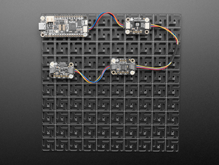 Overhead shot of 10x10 aluminum prototyping grid with a microcontroller and three breakout boards.