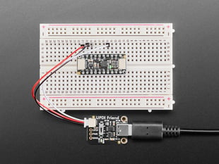 Overhead shot of a half-size breadboard connected to a UPDI board and an AtTiny breakout board. the LEDs light up green on both boards.