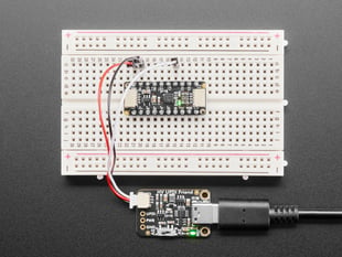 Overhead shot of a half-size breadboard connected to a UPDI board and an AtTiny breakout board. the LEDs light up green on both boards.