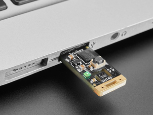 Angled shot of USB key PCB plugged into laptop port.