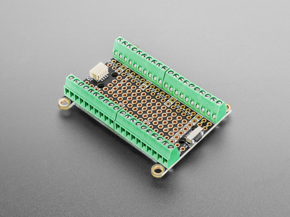 Angled shot of rectangular prototyping PCB lined with green terminal blocks and mounting holes.