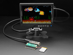 Lifestyle image of black, rectangular doubler prototyping board assembled with a DVI breakout board and a microcontroller. It is hooked up with a small HDMI monitor which displays an aquarium animation.