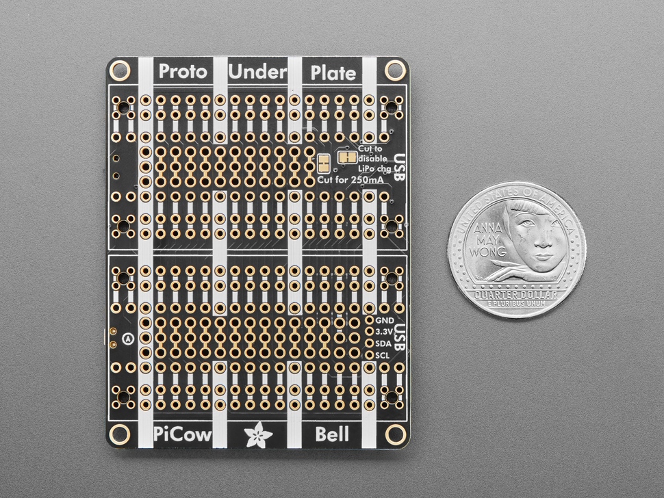 Bottom of black, rectangular doubler prototyping board next to US quarter for scale.