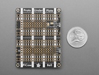 Bottom of black, rectangular doubler prototyping board next to US quarter for scale.