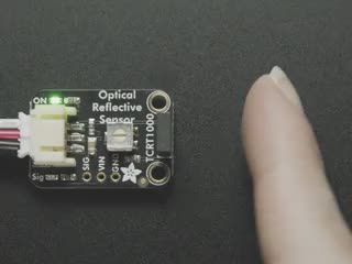 Close-up video of white finger triggering an optical reflective sensor breakout.