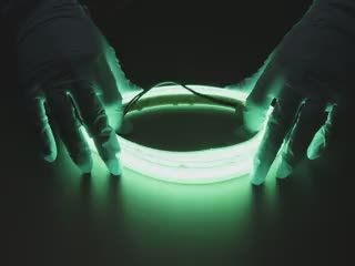 Video of gloved hands playing with a green LED strip.