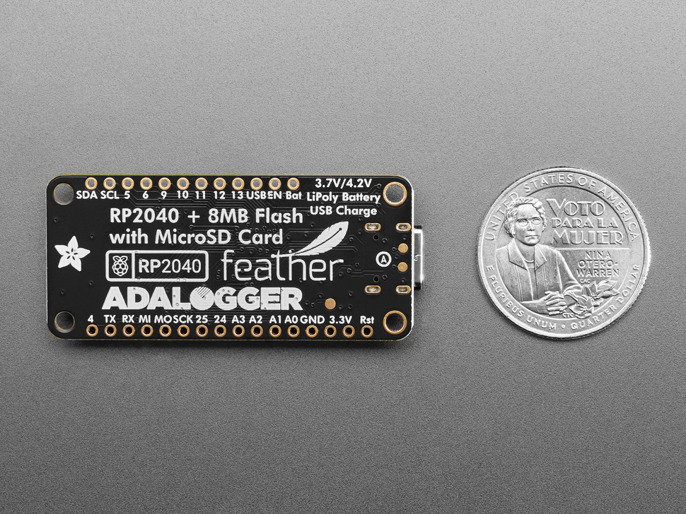 Back of black, rectangular datalogging board next to US quarter for scale.