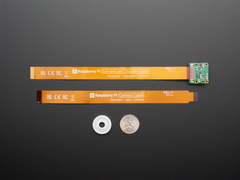 Top Down Back Shot of the Raspberry Pi AI Camera with Included Camera Cables and Adjustable Focus Ring next to a U.S. Quarter for Scale.