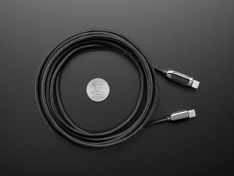 Overhead shot of coiled 2 meter long black woven USB-C cable with US quarter for scale.