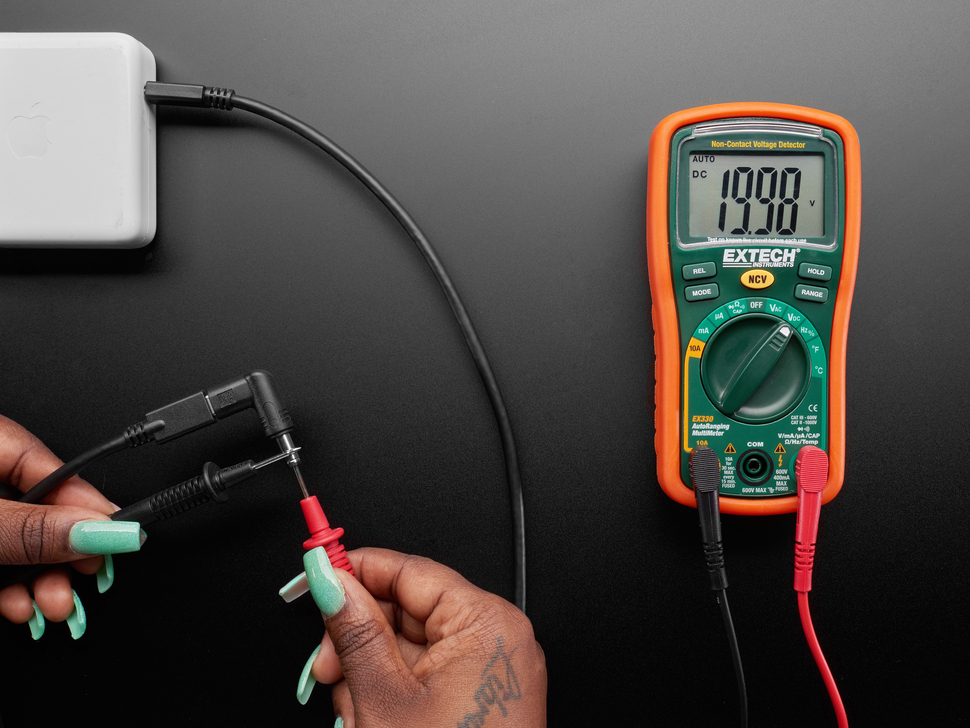 Overhead lifestyle image of cable and adapter hooked up to a multimeter displaying 19.9V.