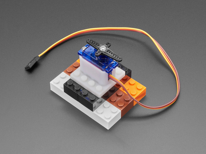 Angled shot of blue micro servo installed in a vertical plastic mount with LEGO bricks.