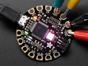 Top down view of a FLORA - Wearable electronic platform: Arduino-compatible connected to 4 alligator clips and a USB powerin the FLORA. 